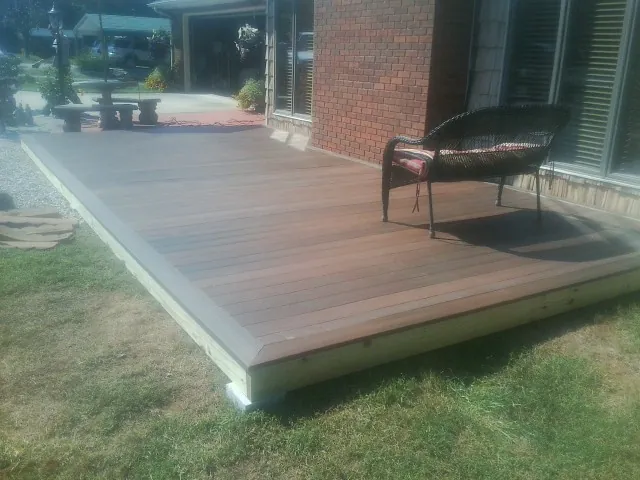 New wood deck and wicker chair beside a brick house in Bloomingdale